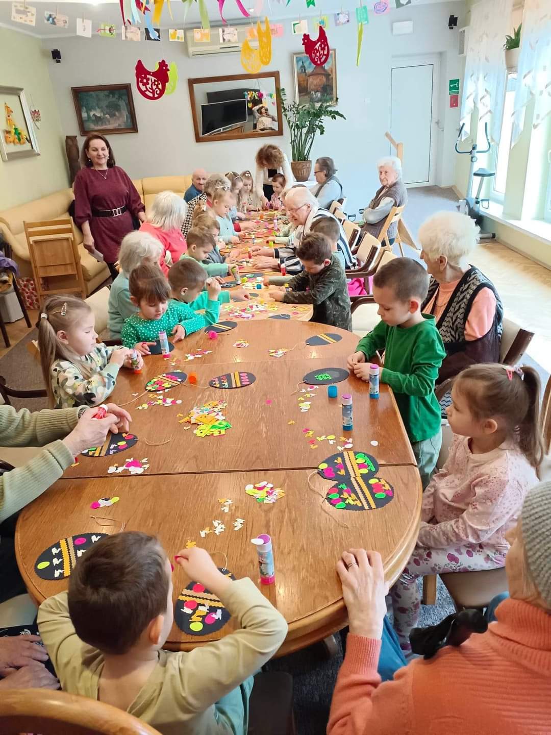 Dzieci wspólnie z seniorami robią dekoracje