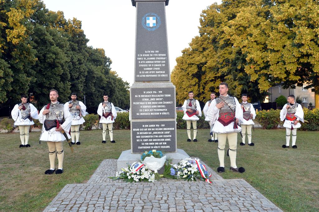 Członkowie greckiego zespołu ustawieni wokół pomnika pamięci w parku im I. Paderewskiego