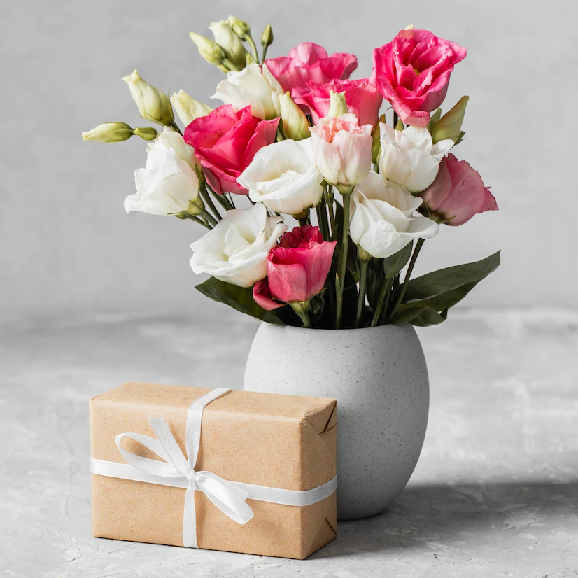 bukiet róż w wazonie obok zapakowanego prezentu